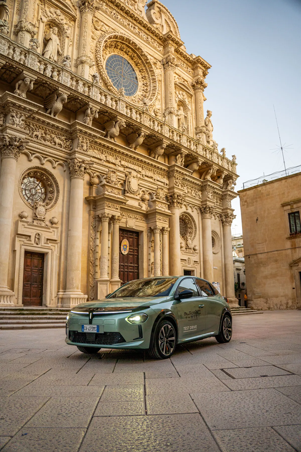 Lancia Ypsilon verde in piazza, davanti alla facciata barocca di Santa Croce