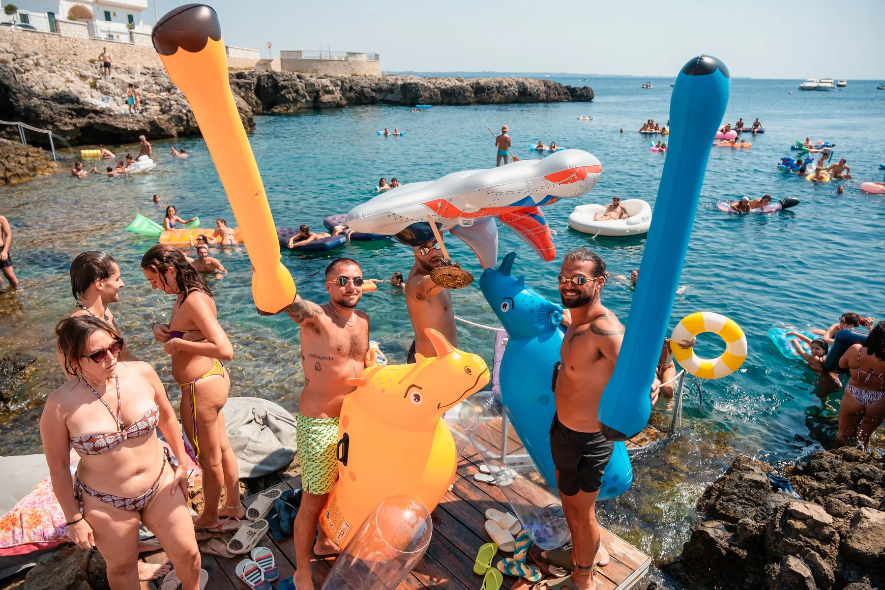 Festa in acqua con gonfiabili davanti agli scogli